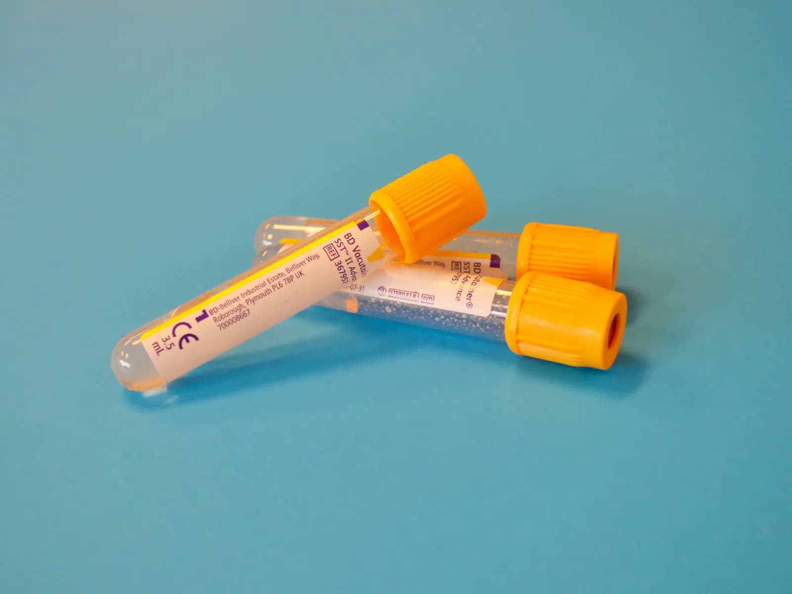 Blood sample tubes with orange caps on a blue surface
